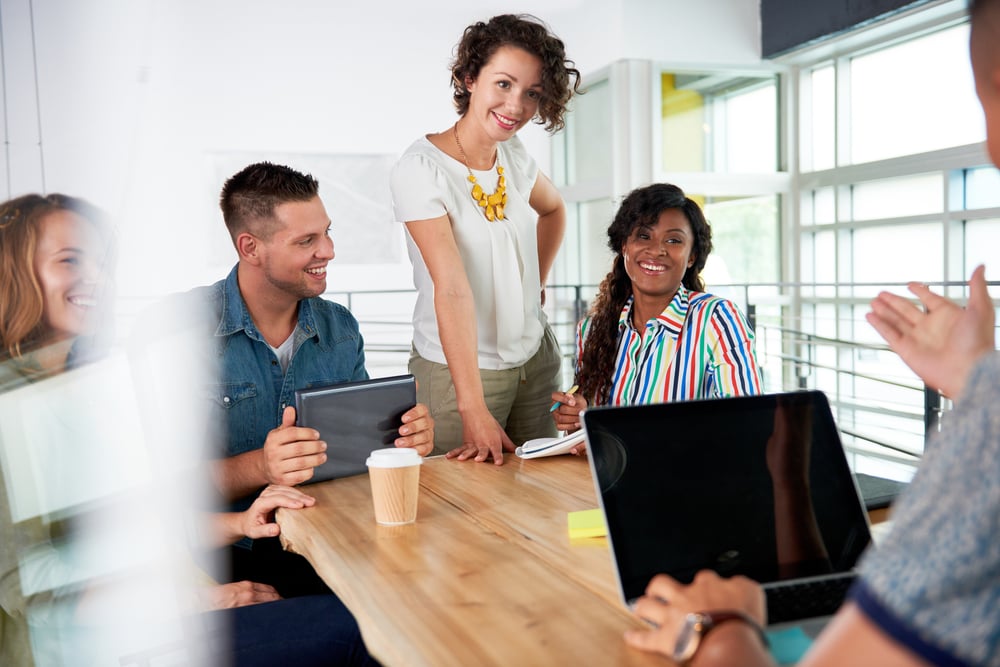 Multi ethnic group of succesful creative business people using a laptop during candid meeting